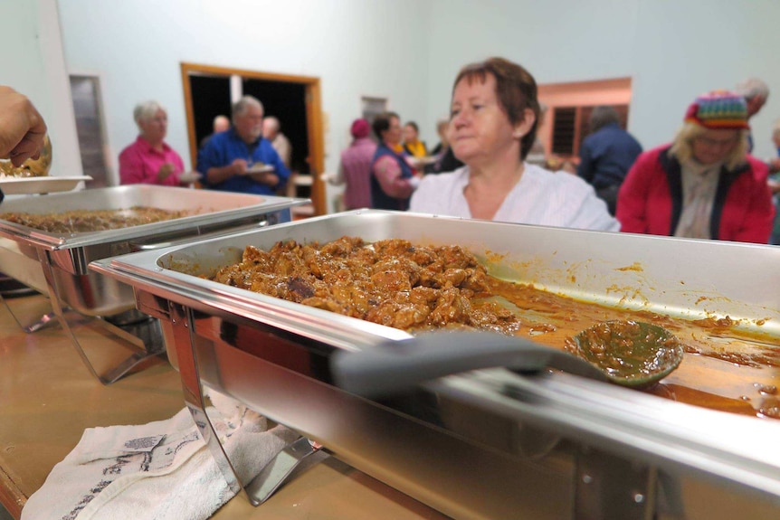 Curries in the foreground, crowded room in the background.