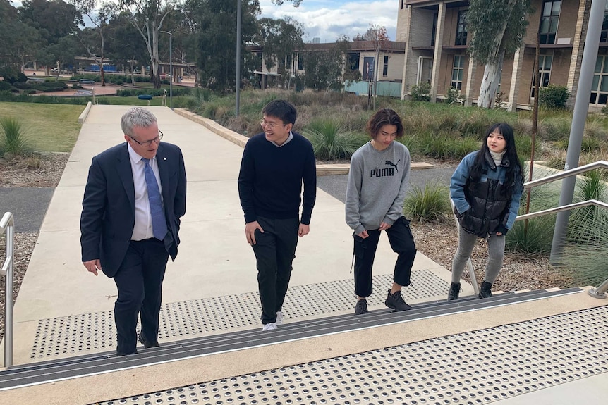 A man walks with international students on a university campus.