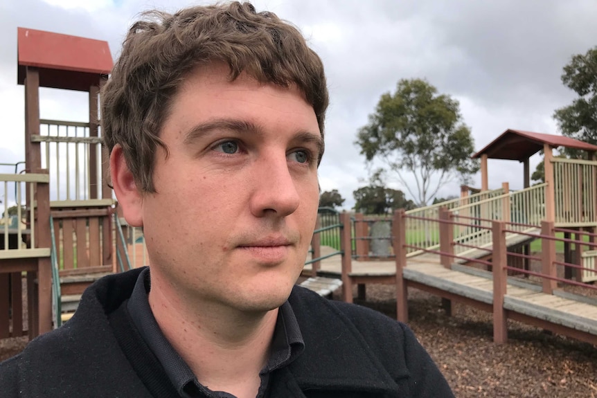 Social worker, Joshua Sherman, standing in front of a playground in a park