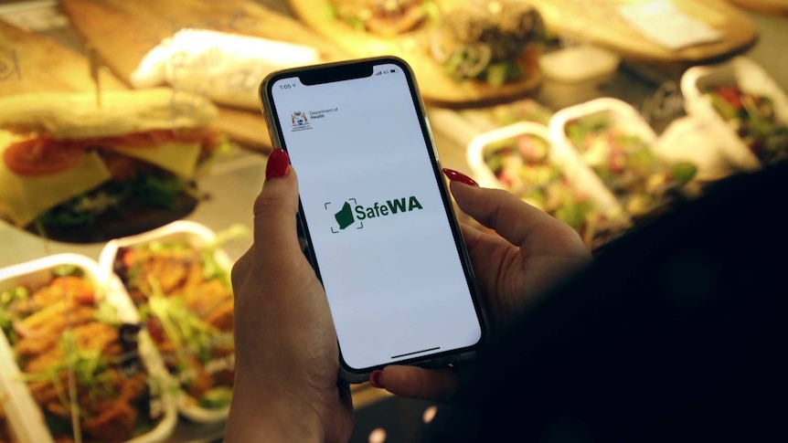 A woman uses the SafeWA app on an iPhone at a cafe in East Perth.