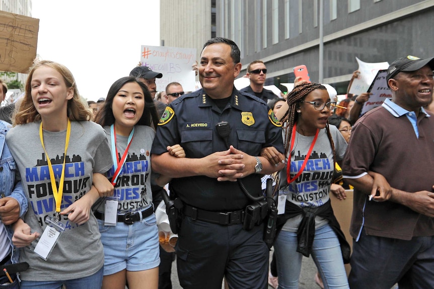 Medium shot of a group of people linking arms and chanting.