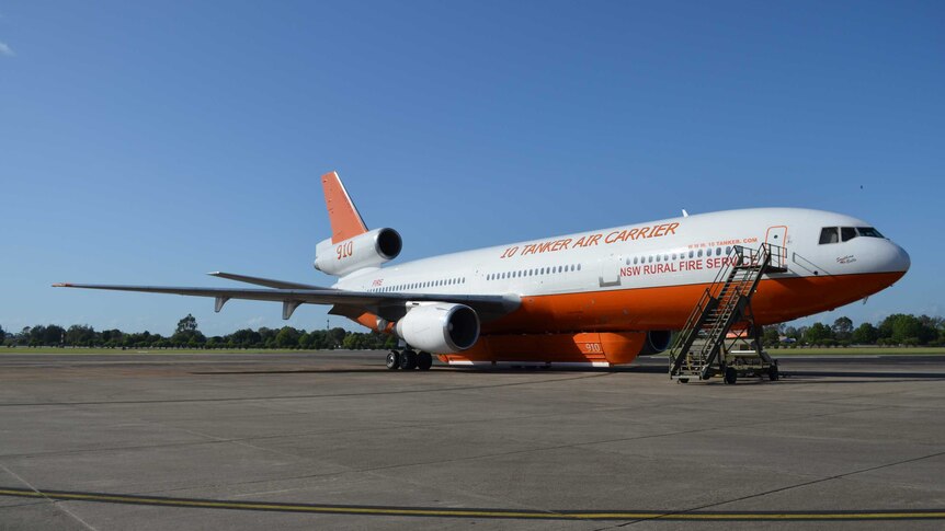 An orange and white DC-10 water-bomber sits on the tarmac.