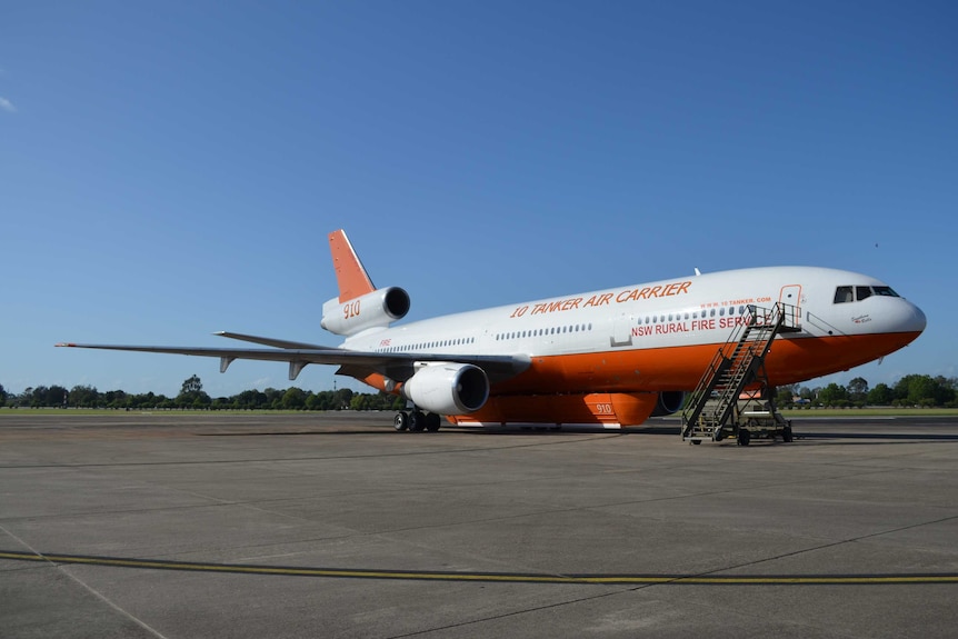 An orange and white DC-10 water-bomber sits on the tarmac.