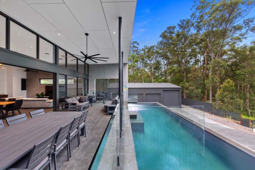 Outdoor entertaining area with pool, trees and shed in background.