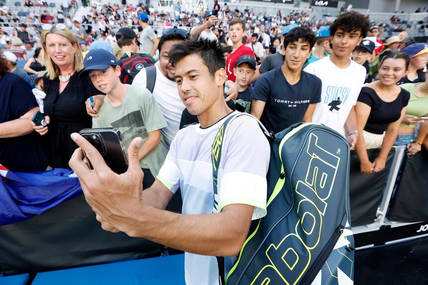 An Australian male tennis player takes a selfie with fans at Melbourne Park.