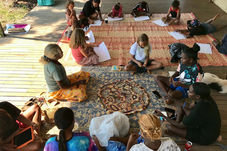 Children and adults sitting working at projects with paper.