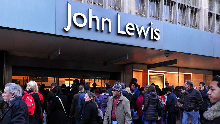 Shoppers queue outside and walk past a John Lewis department store on Oxford Street in central London