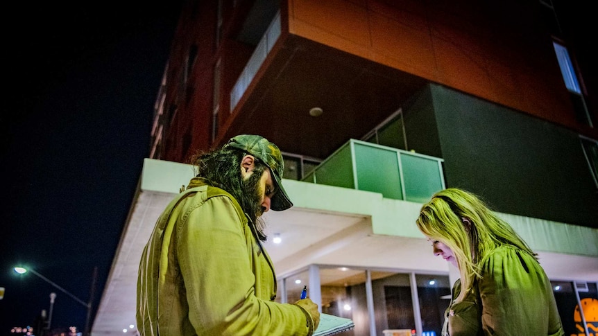 Reporters Mahmood Fazal and Rachael Brown stand in front of the apartment buidling where the Alsehli sisters were found dead.