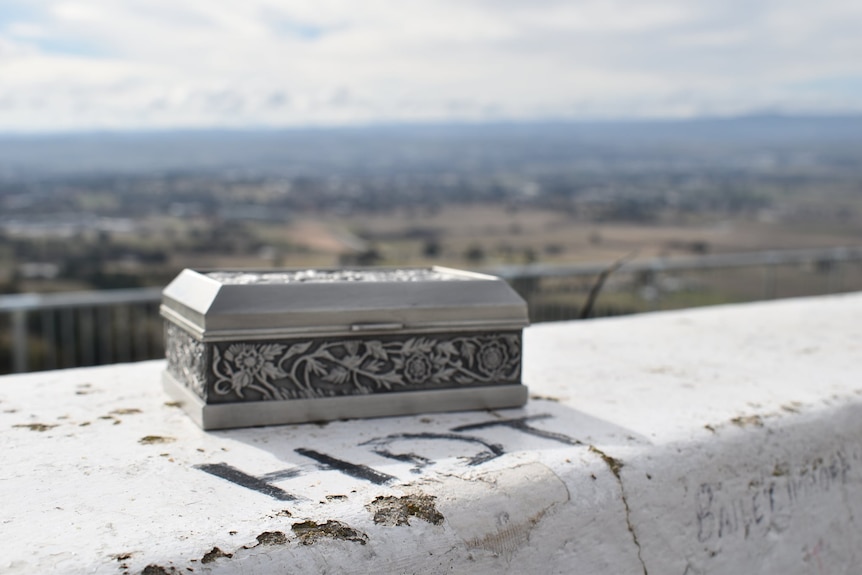 An ornate box sits on a cement barrier overlooking the Bathurst plains. HDT (Holden Dealer Team) is painted on the barrier