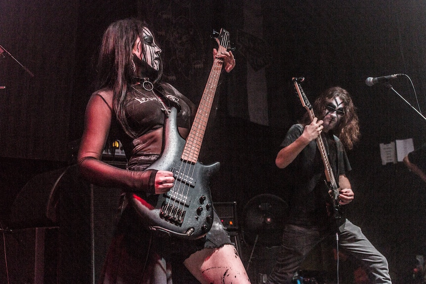 Musical performers holding guitars and wearing makeup.