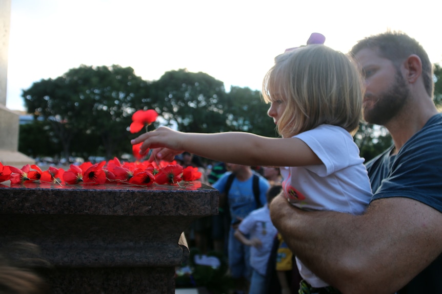 A young girl lays down a poppy at the Cenotaph.