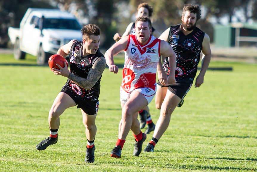 A group of players running during a country rugby league match.