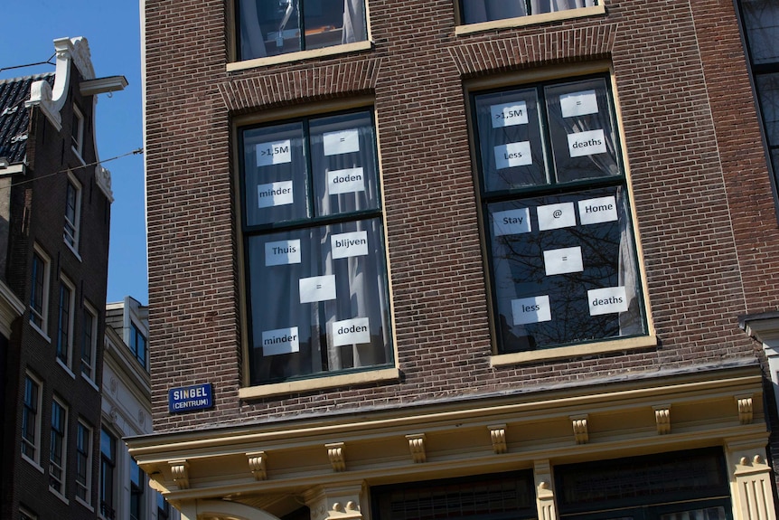 Messages about how to prevent the spread of COVID-19 taped to a window in central Amsterdam.