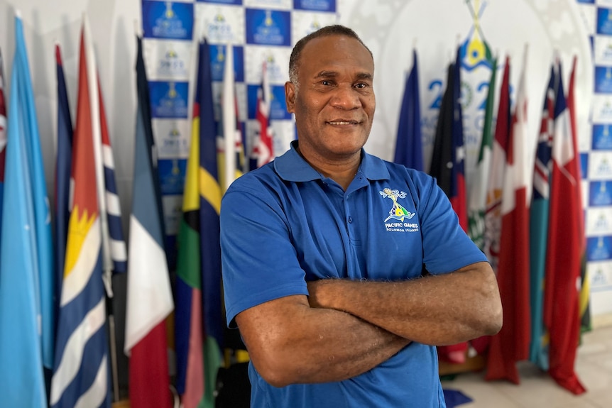 A man smiling with flags in the background