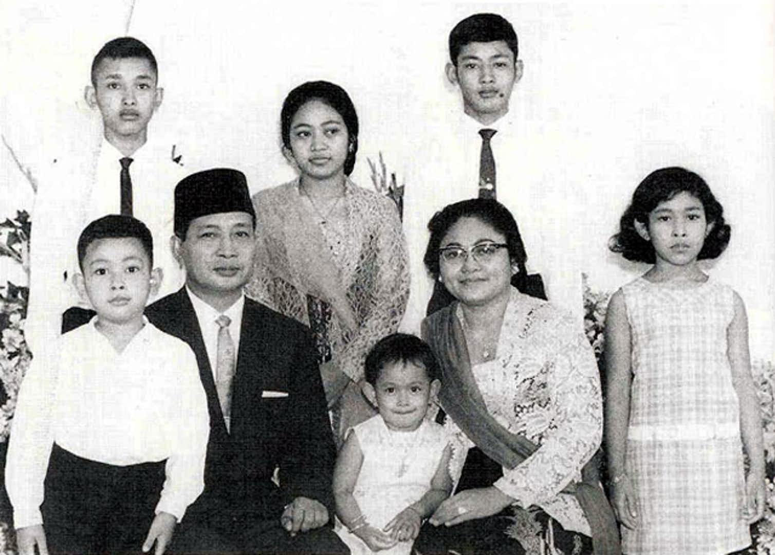 A black and white formal style portrait of Soeharto and his young family