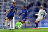 A smiling Sam Kerr runs away from goal towards a teammate as the ball sits in the back of the net. 