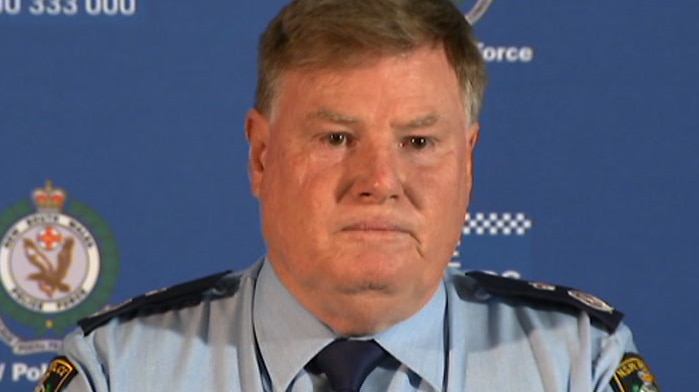 police officer looking stern at a press conference