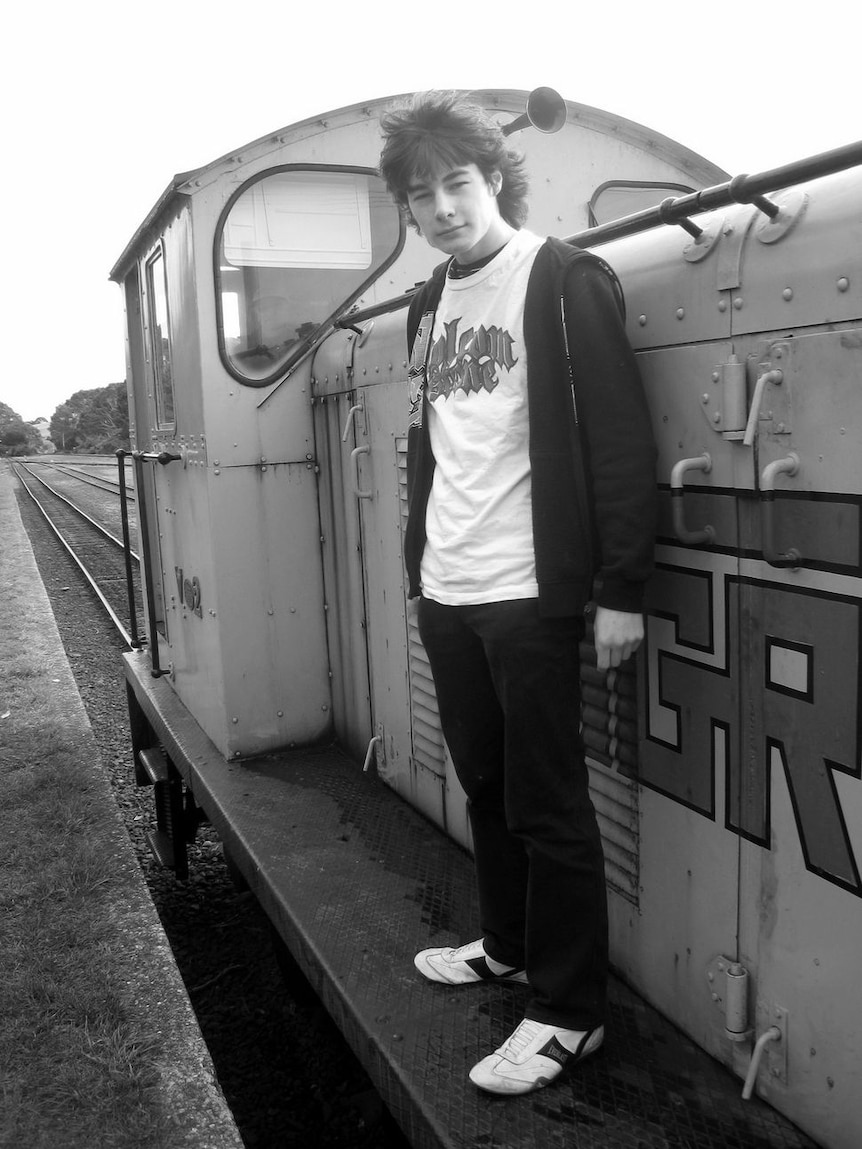Young man standing on the side of a train engine