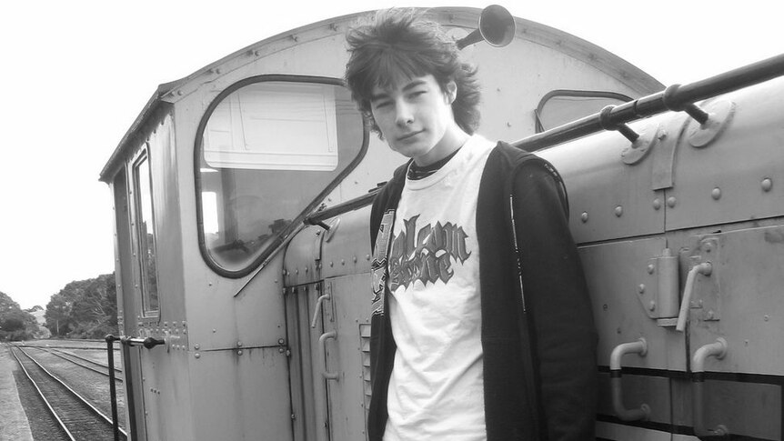 Young man standing on the side of a train engine