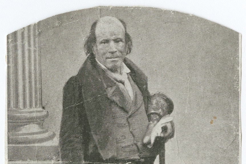 Une photo en noir et blanc de 1860 montre un homme chauve avec les cheveux laissés sur le côté, portant un gilet, une veste, porte une cloche.