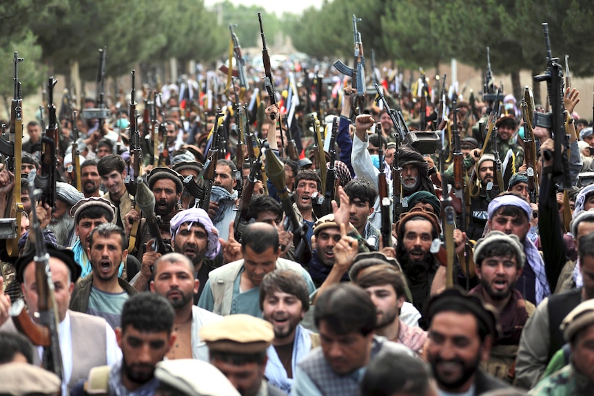 Afghan militiamen join security forces in raising rifles as they crowd together in Kabul