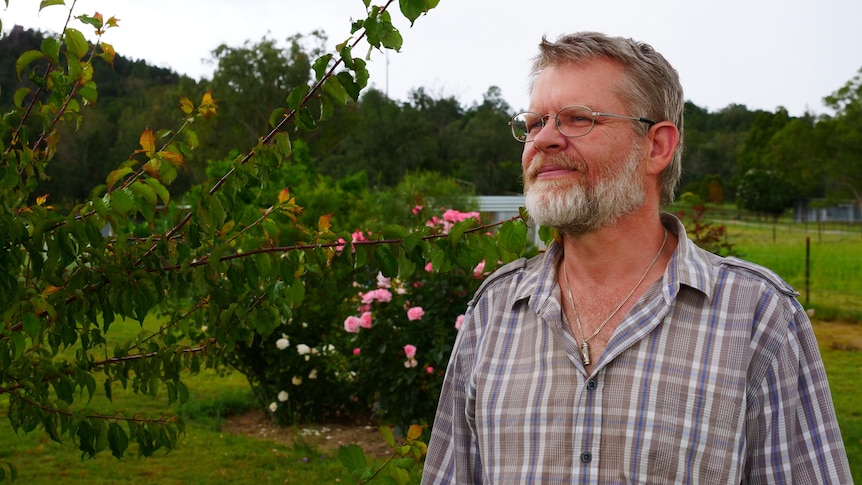 A man stands in front of a rose bush