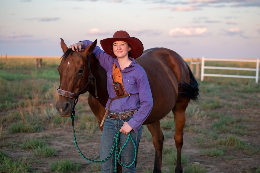 Jacy standing with her horse at sunset on her family property, near Winton, November 2023.