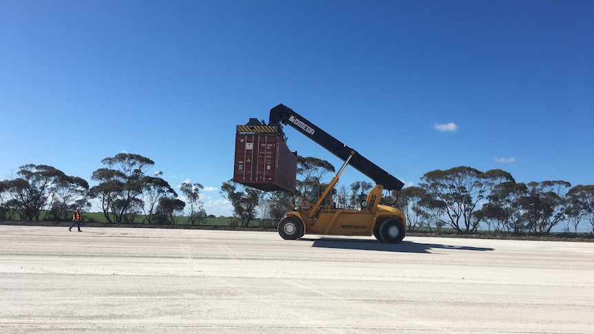 A shipping container is picked up at a loading pad.