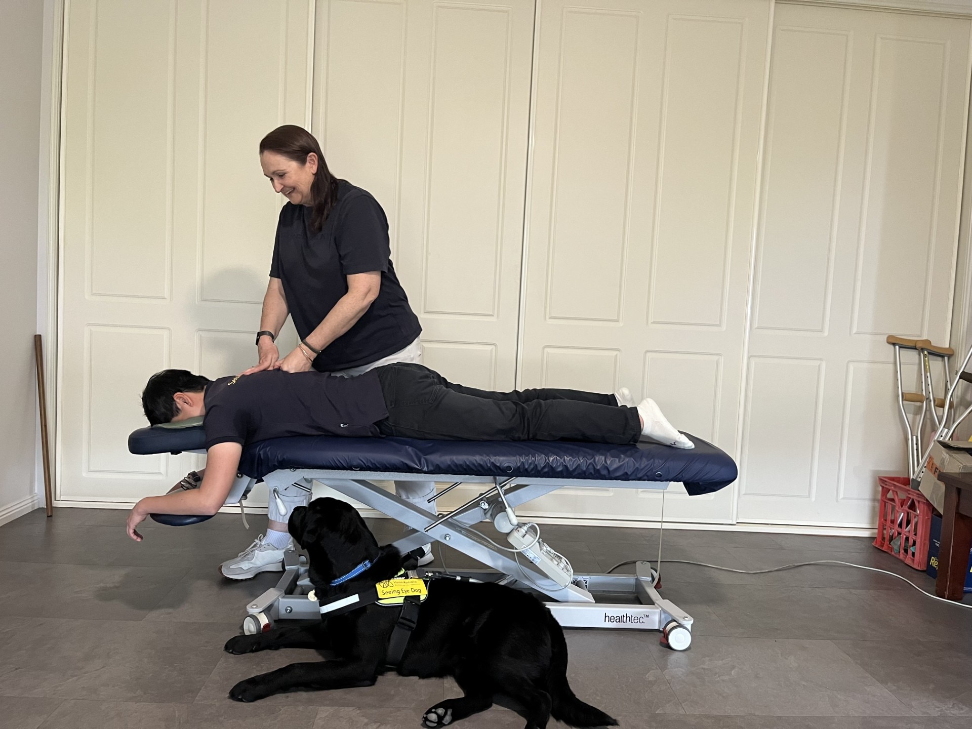 Un fisioterapeuta trata a un paciente mientras un perro guía yace cerca 