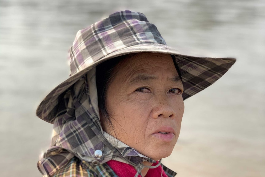 A woman with a wide brimmed hat looks towards the camera.