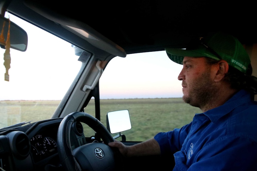 Inside the vehicle, Jamie Black looks forwards, driving his ute through open country