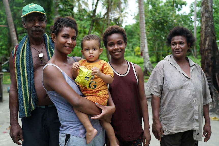 Baby Christopher in the arms of his mother, surrounded by his family on Manus Island