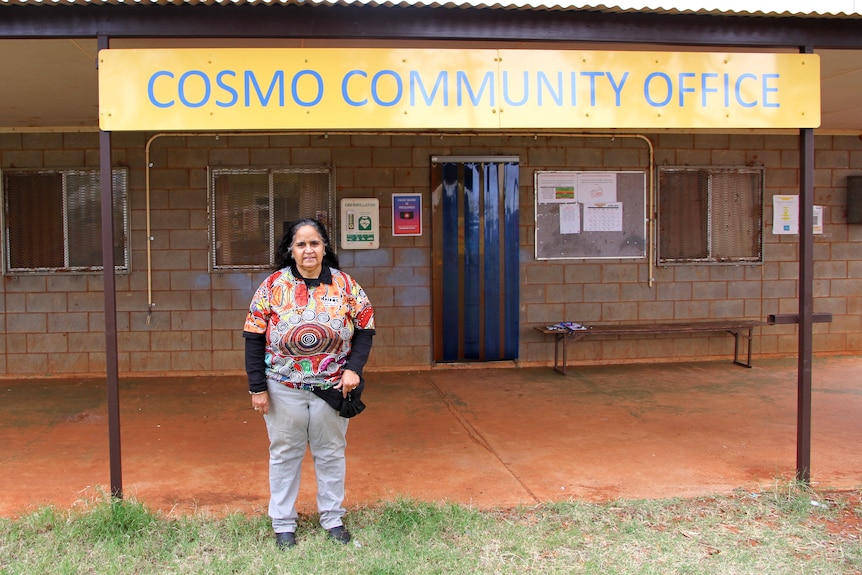 Gwen Murray stands in front of a sign saying 'Cosmo Community Office'