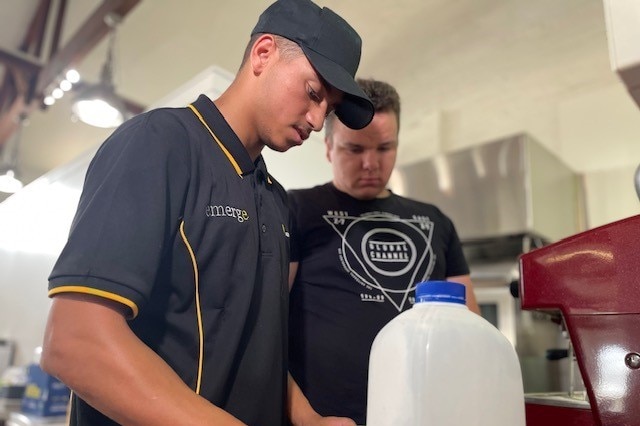 A boy shows another boy how to make a coffee.