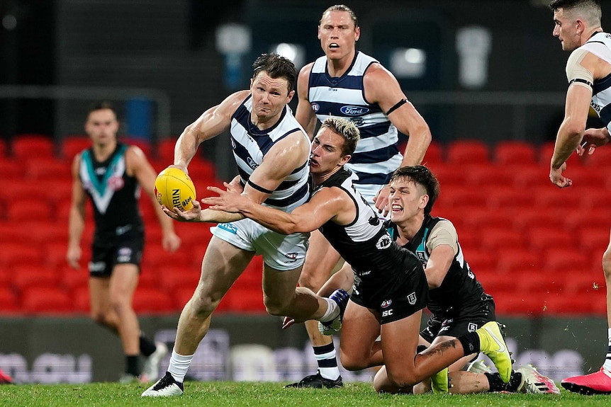 Patrick Dangerfield tries to get a handball away while being tackled