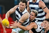 Patrick Dangerfield tries to get a handball away while being tackled