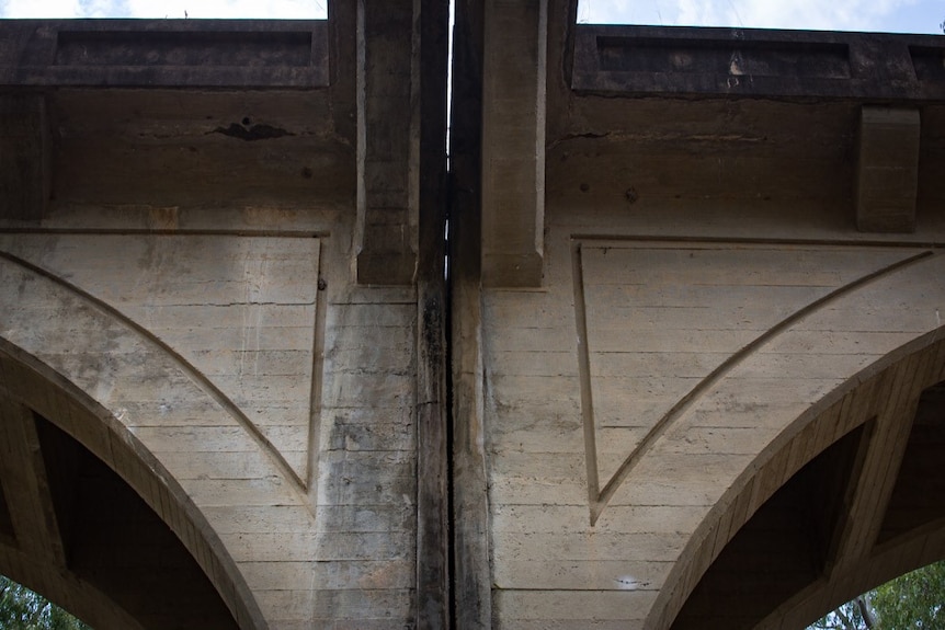 A close-up shot of the concrete arch of a bridge.
