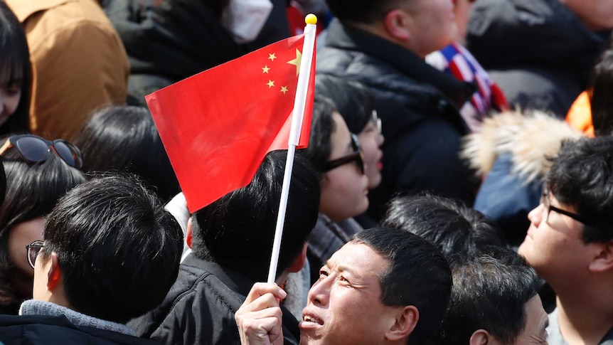 A man in the crowd holds a Chinese flag