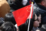 A man in the crowd holds a Chinese flag