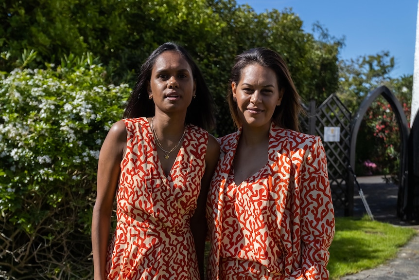 Cassie Puruntatameri and Shannon McGuire photographed in elegant patterned clothing in a garden. 