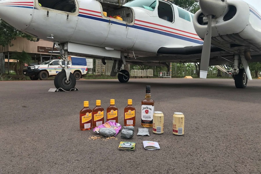Drugs and alcohol are placed on the tarmac below a chartered fixed-wing plane.