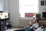 A photo of James Findlay sitting on the ground in front of his TV, celebrating Christmas alone in England in 2011.