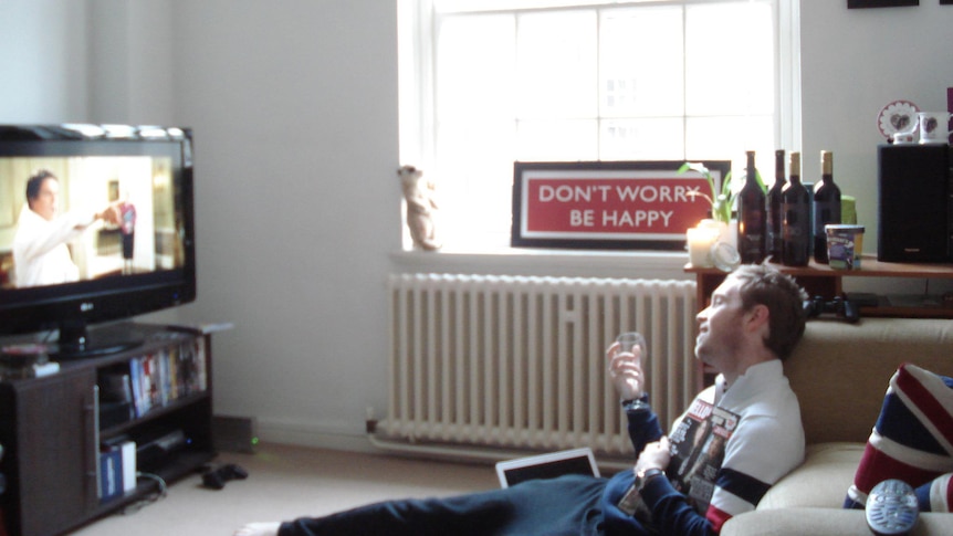 A photo of James Findlay sitting on the ground in front of his TV, celebrating Christmas alone in England in 2011.