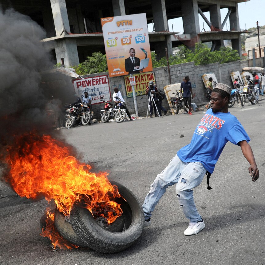 A man kicks burning tires during a protest 