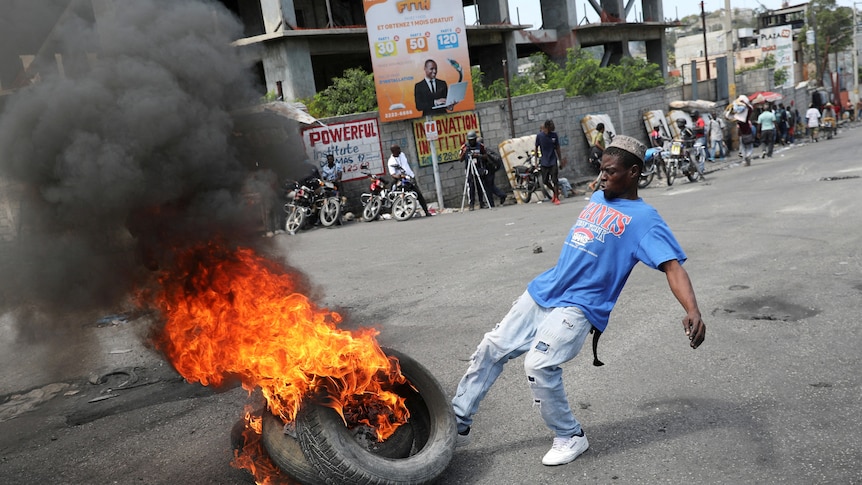 A man kicks burning tires during a protest 