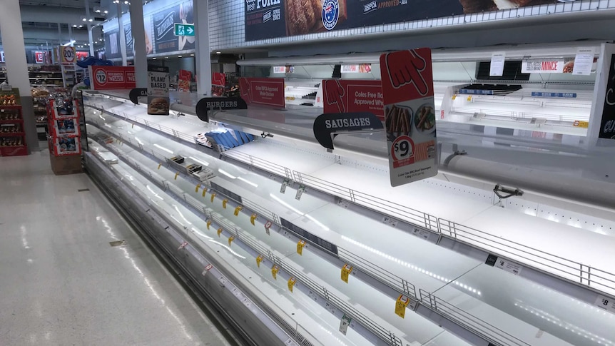 The meat shelves at a supermarket are nearly entirely empty.