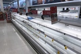 The meat shelves at a supermarket are nearly entirely empty.
