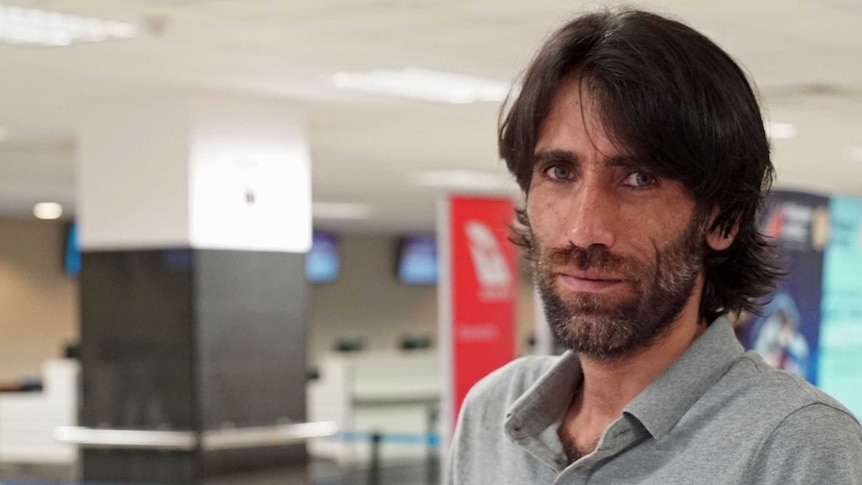 Behrouz Boochani stands inside an airport terminal.