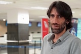 Behrouz Boochani stands inside an airport terminal.