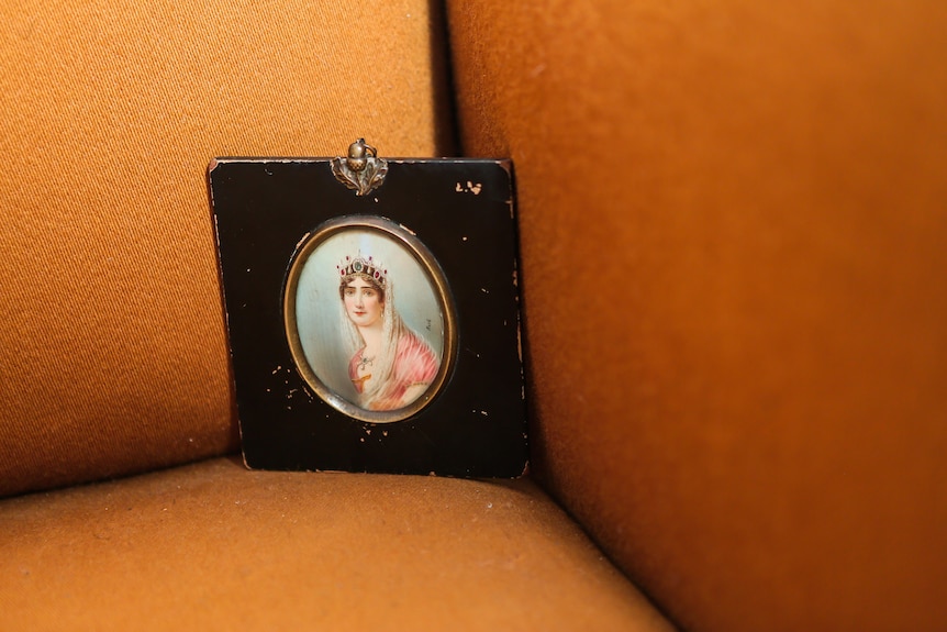 A photo of a painted oval portrait from the 1800s of a woman with a crown and a pink dress